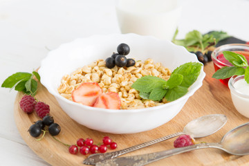 Tasty cornflakes with berries on wooden background Healthy tasty breakfast of muesli with strawberries, raspberries, black currants and red currants.