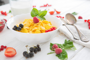 Fresh corn flakes with strawberries and milk close up Healthy tasty breakfast cornflakes with strawberries, raspberries, black currants and red currants.