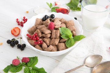 chocolate cereal pads with berries in bowl Healthy tasty breakfast chocolate square pads with strawberries, raspberries, black currants and red currants.