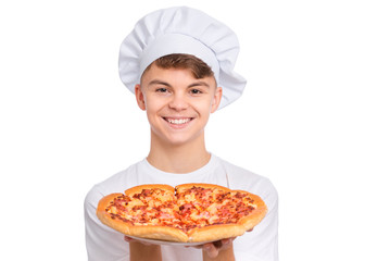 Happy handsome teen boy in chef hat holding cooked appetizing pizza. Guy holds plate with fresh pizza in his hands, isolated on white background. Portrait of cute child showing delicious Italian pizza