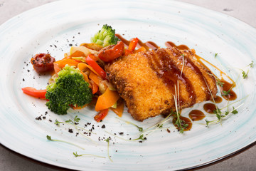 Breaded fish cutlet served with grilled vegetables