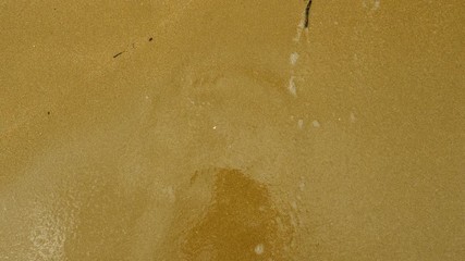 Emoji. Top view of the wave washing away the sad face drawn on the sand of sandy beach of Mediterranean sea. 4K