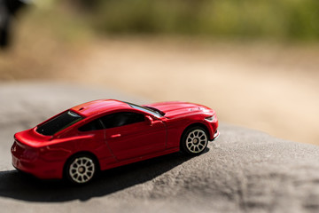 Fototapeta na wymiar Red toy car on a blurred background. Selective focus. Travel concept.