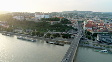 Fototapeta premium Bratislava Aerial Cityline (Slovakia): European Capital with Old Town, Castle, Church and Most SNP (Ufo Car Road Bridge) across Danube River at Sunset