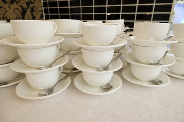 Stacked empty teacups with teaspoons and plates