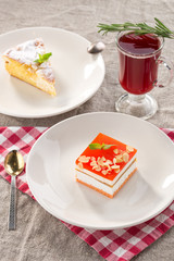 Set of two desserts apple sponge cake and vanilla souffle cake with cranberry tea on grey tablecloth