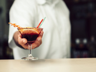 Male bartender serving vibrant drink in martini glass