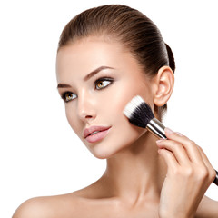 woman  applying cosmetic makeup on the face with brush