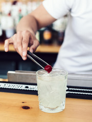 Fototapeta na wymiar Male bartender adding cherry into drink