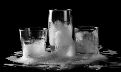 Drinking glass and cleaning, washing foam isolated on black background