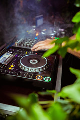 Obraz premium Close up view of the hands of a male disc jockey mixing music on his deck with his hands poised over the vinyl record on the turntable and the control switches at night