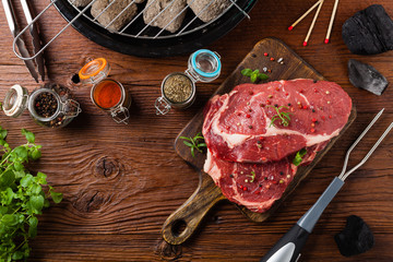 Raw beef steak, ready for grilling. Grill accessories. Concept. Free space for description. Top...