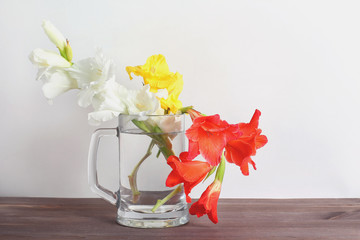 bouquet of gladioli in a glass vase on a wooden table