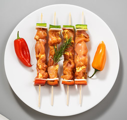 raw chicken skewers on white dish