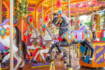 Fototapeta na wymiar Old French carousel in a holiday park. Three horses on a traditional fairground vintage carousel. Merry-go-round with horses.