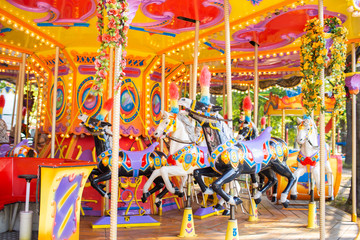 Old French carousel in a holiday park. Three horses on a traditional fairground vintage carousel. Merry-go-round with horses.