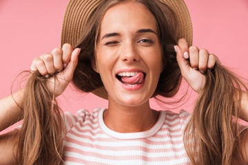 Image closeup of young joyful woman wearing straw hat making fun with her hair while grimacing and...
