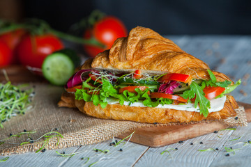 Croissant sandwiches served on wooden board. Croissants with egg, melted cheese, parsley, chicken ham, smoked salmon