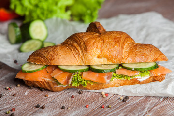 Croissant sandwiches served on wooden board. Croissants with egg, melted cheese, parsley, chicken ham, smoked salmon