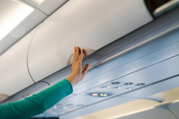 Stewardess checking luggage cabin in airplane