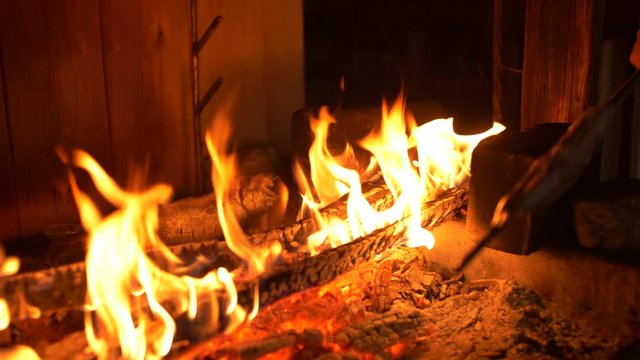 Medium close-up shot of placing a skewer of Saibling char fish next to a burning wood fire pit