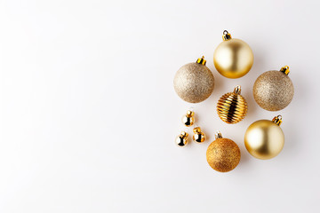 Trendy metallic gold Christmas shiny and matte balls on wite background with copy space