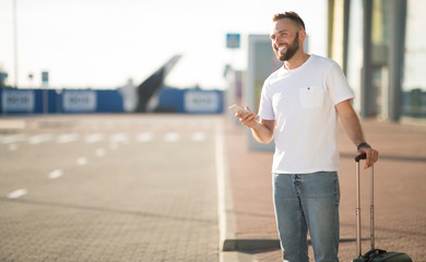 Man arriving at airport, waiting cab and using phone