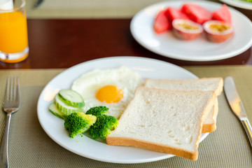 Fototapeta na wymiar Fresh romantic breakfast table next to window with bread, fruit, juice, milk, egg, vegetable...