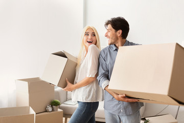 Young Couple Carrying Moving Boxes Relocating To New Place
