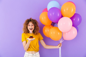 Image of happy young woman celebrating birthday with multicolored air balloons and piece of pie