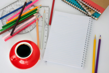 Red coffee cup with black coffee resting on a white desk, top view