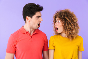 Portrait of stressed young couple man and woman expressing outrage with open mouthes while looking at each other