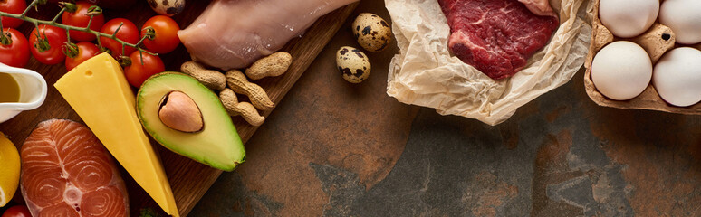 Panoramic shot of wooden cutting board with raw fish and poultry near vegetables, cheese, meat,...