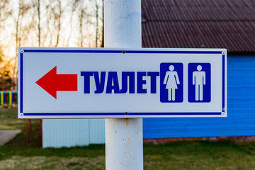 Signpost on the street in the form of an arrow and the words "toilet"