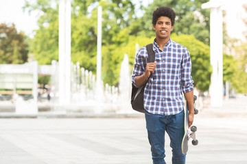 Handsome male teenager with skateboard posing to camera