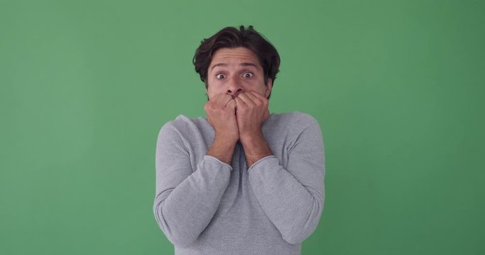 Shocked man feeling nervous and scared over green background
