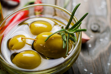 Closeup view of green olives oils and spices on kitchen table. Cooking concept