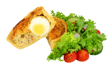 Scotch egg quiche with shortcrust pastry and whole egg encased in pork sausage meat with fresh salad isolated on a white background