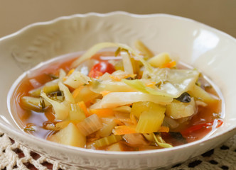 Weight loss celery and cabbage dietary Bonn soup in white vintage plate on handmade knitted napkin