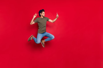 Full size photo of cool guy jumping high making selfies show v-sign wear casual outfit isolated on red background