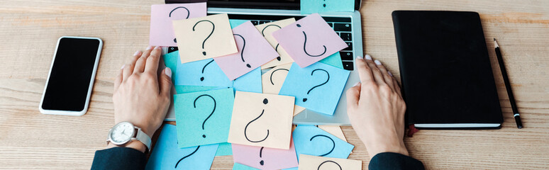 panoramic shot of woman near sticky notes with question marks on laptop