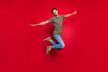 Full body photo of overjoyed guy jumping high like bird flight wear casual outfit isolated on red...