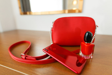 set of red women's accessories - bag, phone, perfume. stylish red handbag and phone on the table with space for text.red bottle with perfume.things stylish fashionable girl