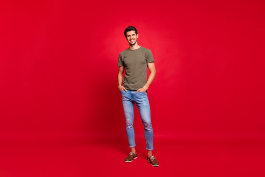 Full length photo of macho guy hold hands pockets street look wear casual outfit isolated on red background