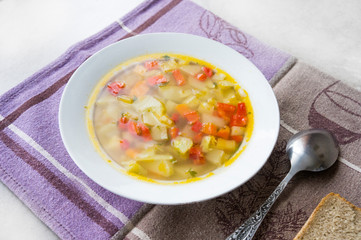 Soup with fresh vegetables in a plate on a napkin