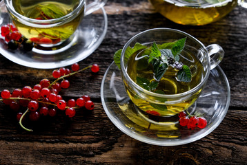  Green herbal tea with a berries in glass cup on wooden table background