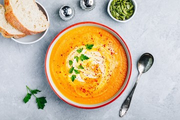 Carrot and pumpkin cream soup with parsley on gray stone background. - obrazy, fototapety, plakaty