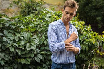 Young handsome man in casual clothes  pose in summer garden.