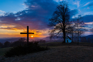 Zachód słońca nad krzyżem i kapliczką.