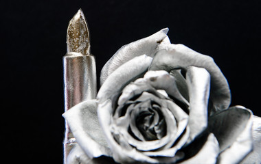 Metallic silver color. Metal flower and lipstick. Forging and sculpture. Silver metal. Silver fashion. Cosmetics and beauty supplies. Lip balm care and lipstick. Makeup concept. Fashion makeup